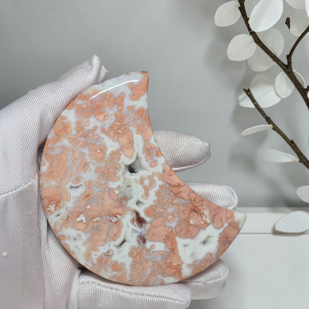 Close view of peach and pink Cotton Candy Agate moon with creamy white patterns