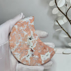Close view of peach and pink Cotton Candy Agate moon with creamy white patterns