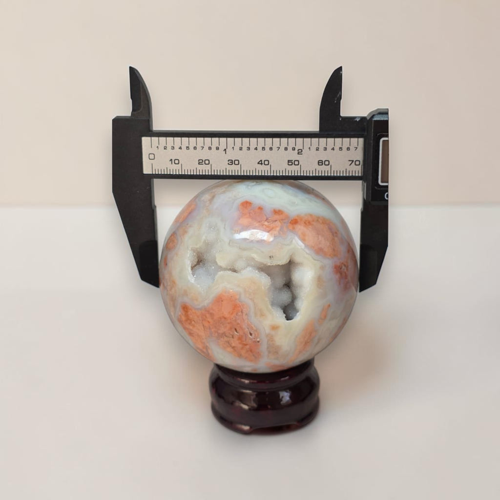 Agate sphere on dark stand shown with a ruler measuring about 70mm