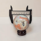 Agate sphere on dark stand shown with a ruler measuring about 70mm