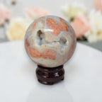 Agate sphere with white and orange swirls, glossy finish on dark wood stand