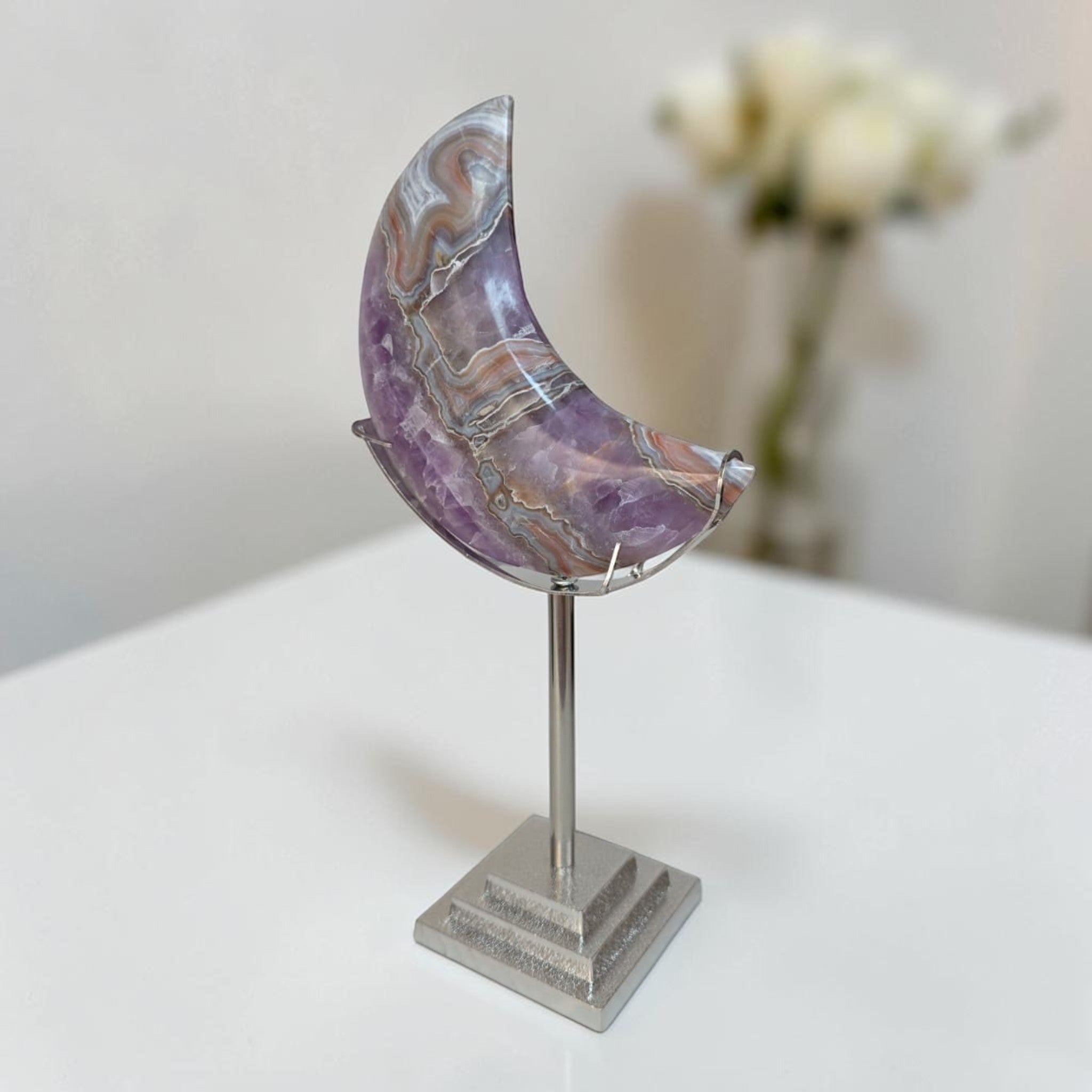 Purple banded agate crescent moon on silver stand, angled view