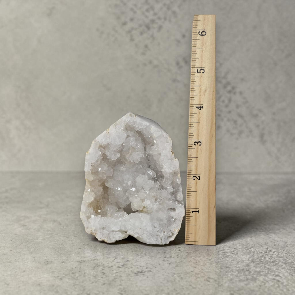 White quartz drusy geode with sparkling crystals next to a measurement ruler.