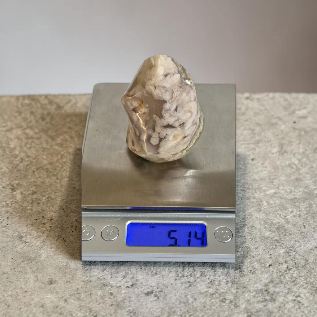 Agate flame crystal on a digital scale, clear beige with white mineral inclusions