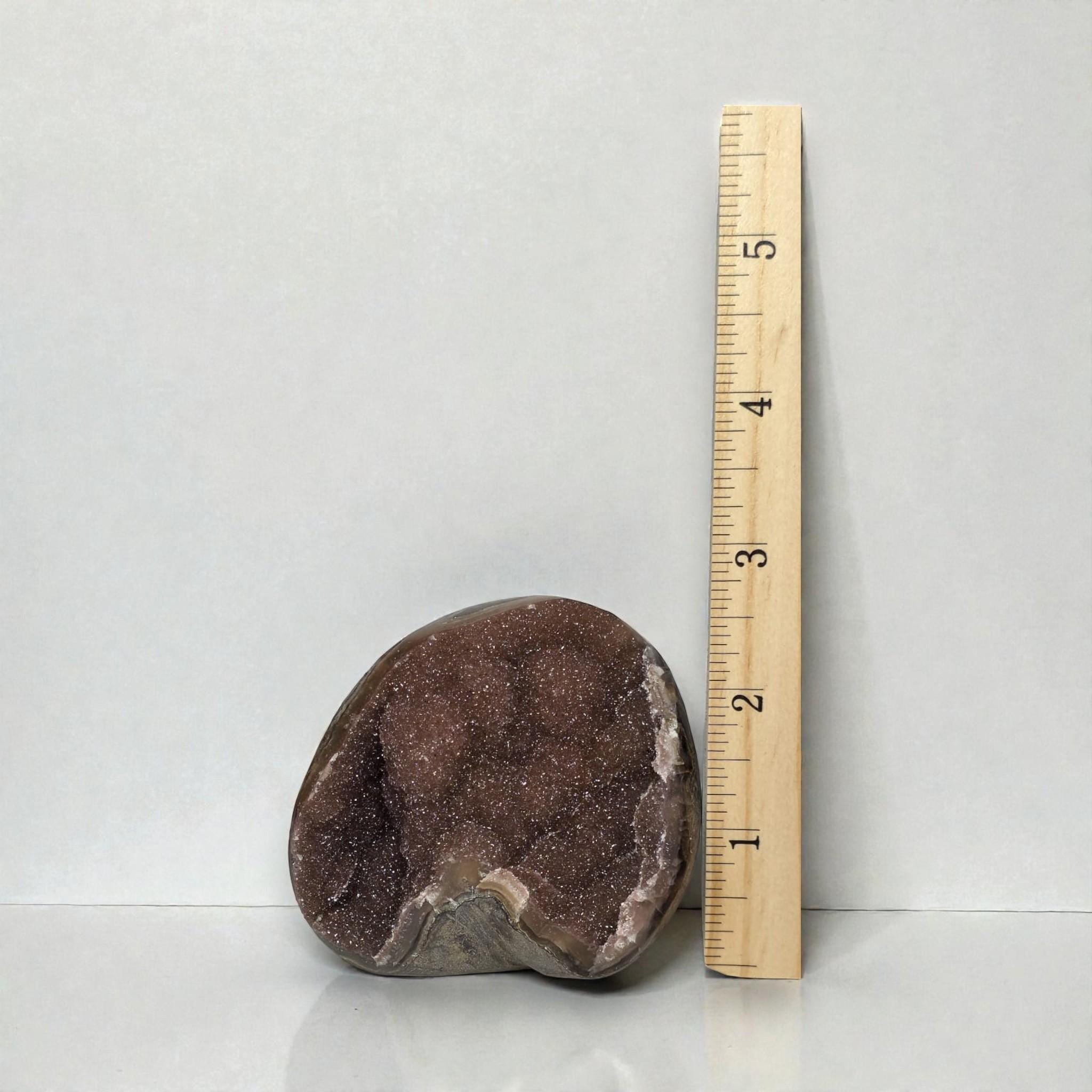 Amethyst quartz druzy freeform stone with dark purple sparkly face, beside ruler.