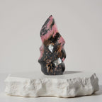 Rhodonite flame-shaped crystal carving with pink and black mottled veining, polished