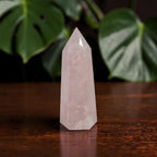 Rose quartz crystal tower with light pink prism facets and sharply pointed tip
