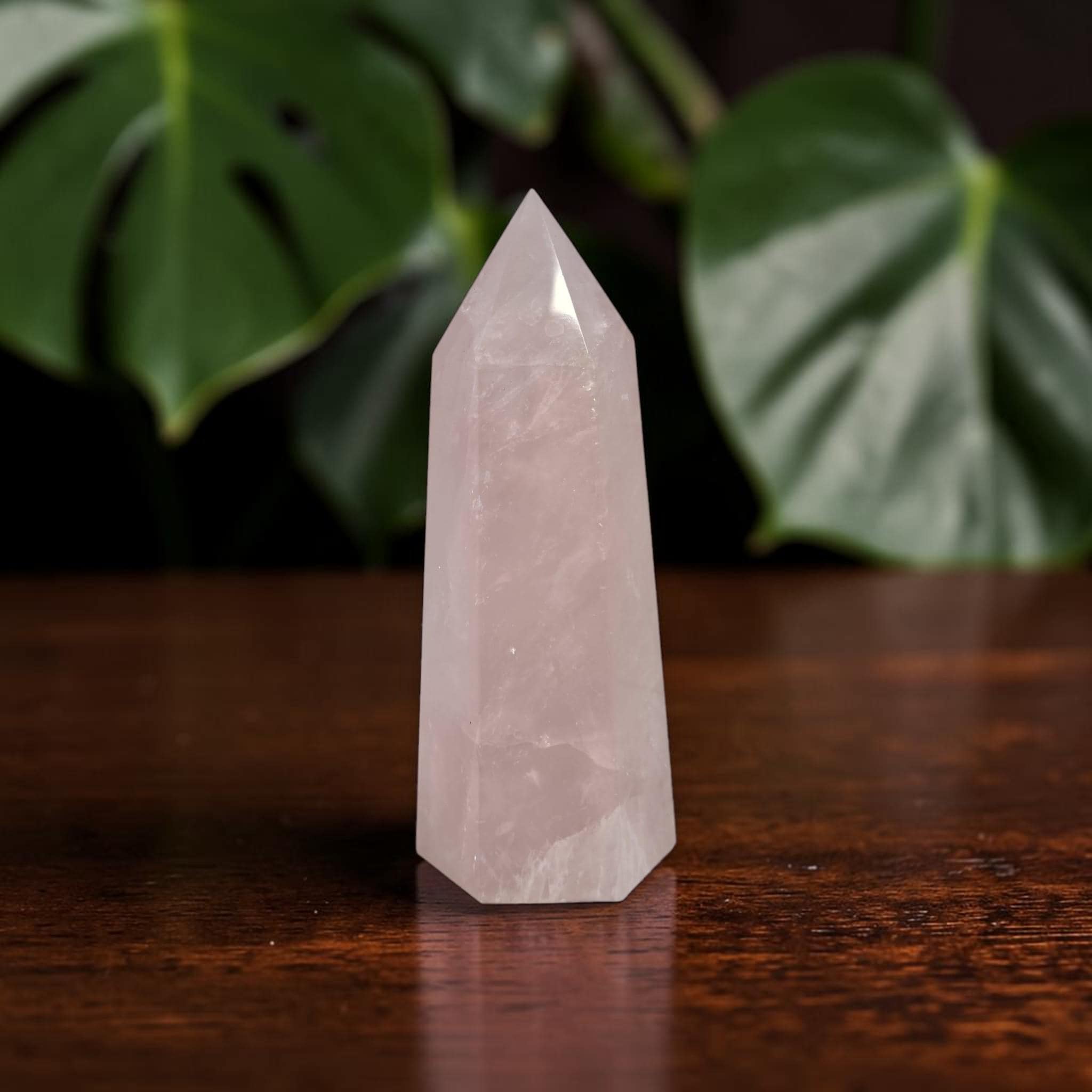 Rose quartz crystal tower with light pink prism facets and sharply pointed tip