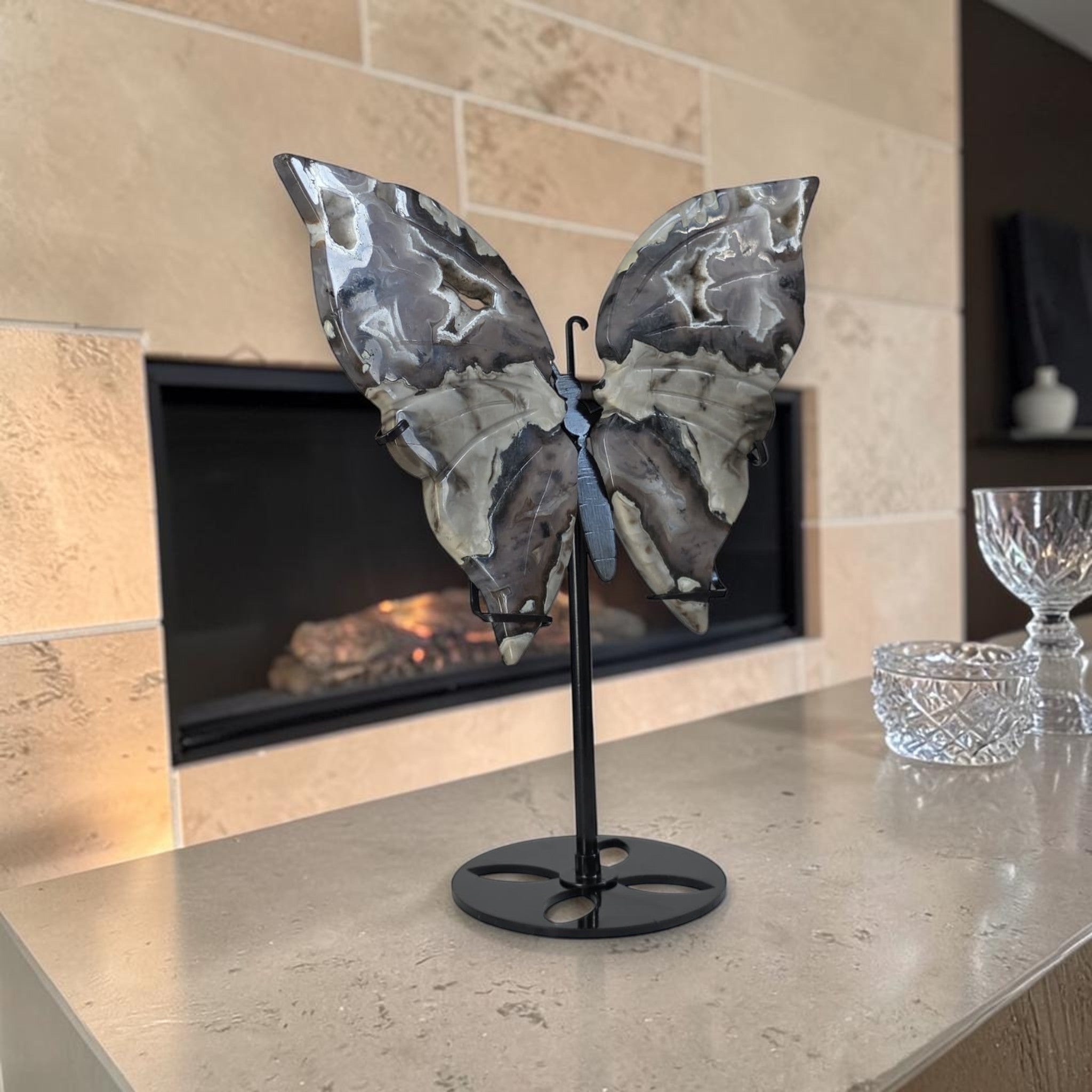 Butterfly sculpture on a stand in front of a fireplace