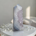 Geode crystal on a white surface with small white flowers