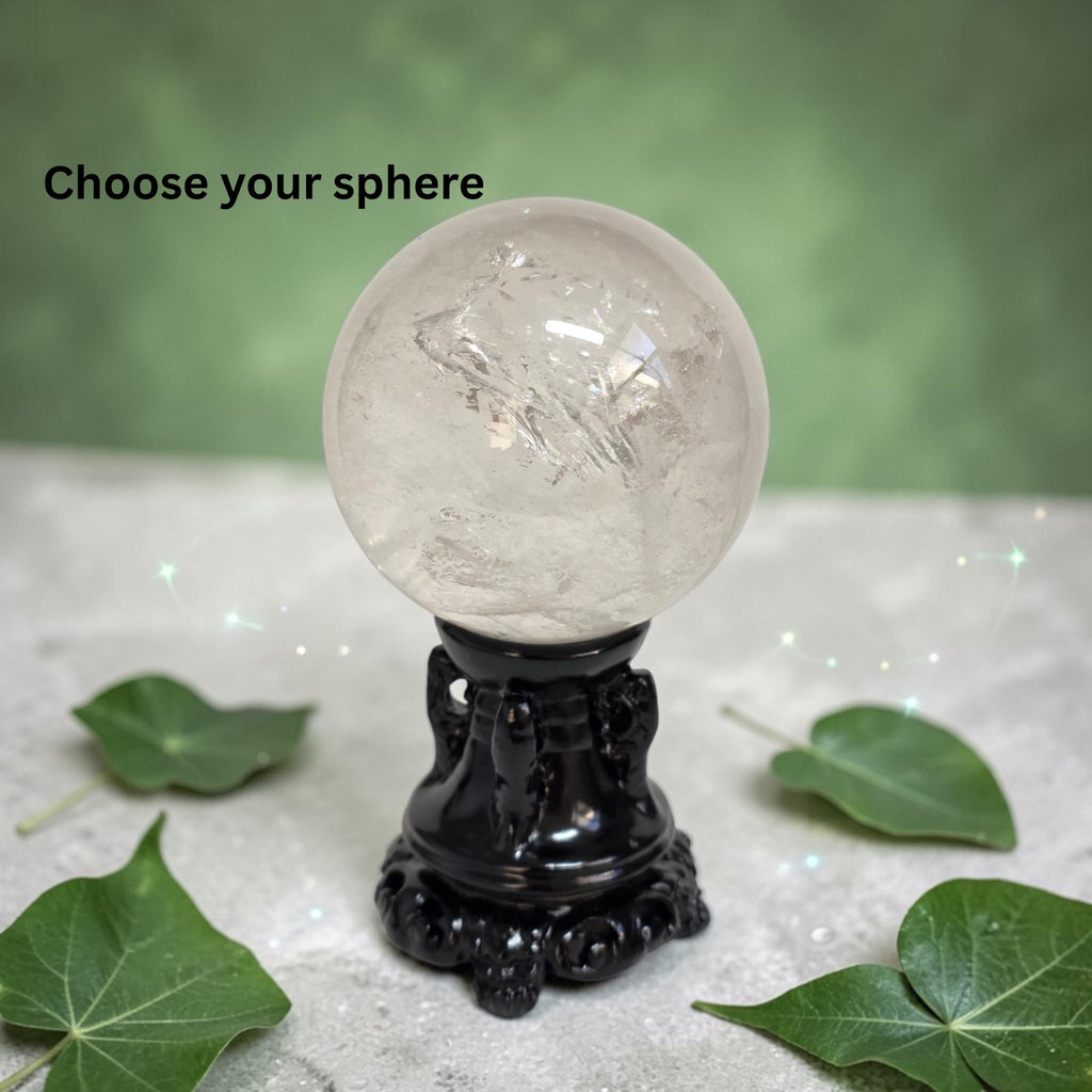 Clear quartz sphere on black ornate base, glossy polished surface with bright highlights