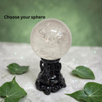 Clear quartz sphere on black ornate base, glossy polished surface with bright highlights