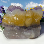 Eagle crystal carving with yellow body, purple wings, and gray natural stone base