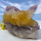 Eagle crystal sculpture with yellow center, purple feather tips, on gray stone base