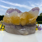 Eagle crystal carving with yellow body and purple wing accents on a gray stone base