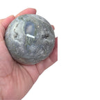 Grey agate geode sphere held in hand, close-up of cavity and textured druzy areas