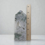 Moss agate crystal obelisk beside measuring ruler; white translucent stone with green inclusions.