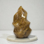 Golden quartz flame-shaped crystal sculpture on a round stone base