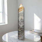 Polished banded calcite obelisk with stacked white, gray and tan mineral bands