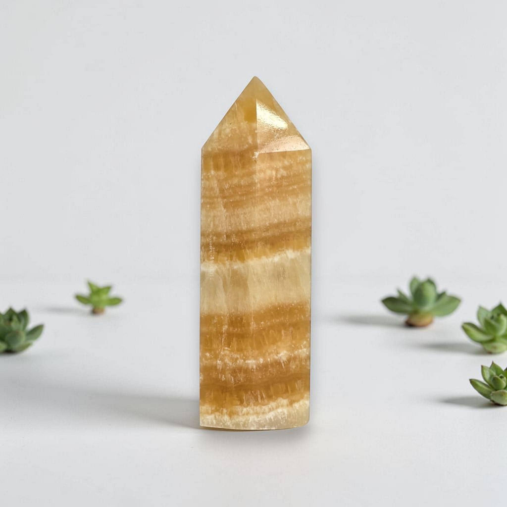 Honey-yellow calcite tower mineral point with horizontal banding and pointed polished tip.