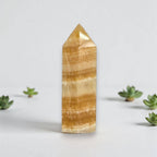 Honey-yellow calcite tower mineral point with horizontal banding and pointed polished tip.