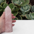 Hand-held pale pink rose quartz tower with faceted sides and pointed tip