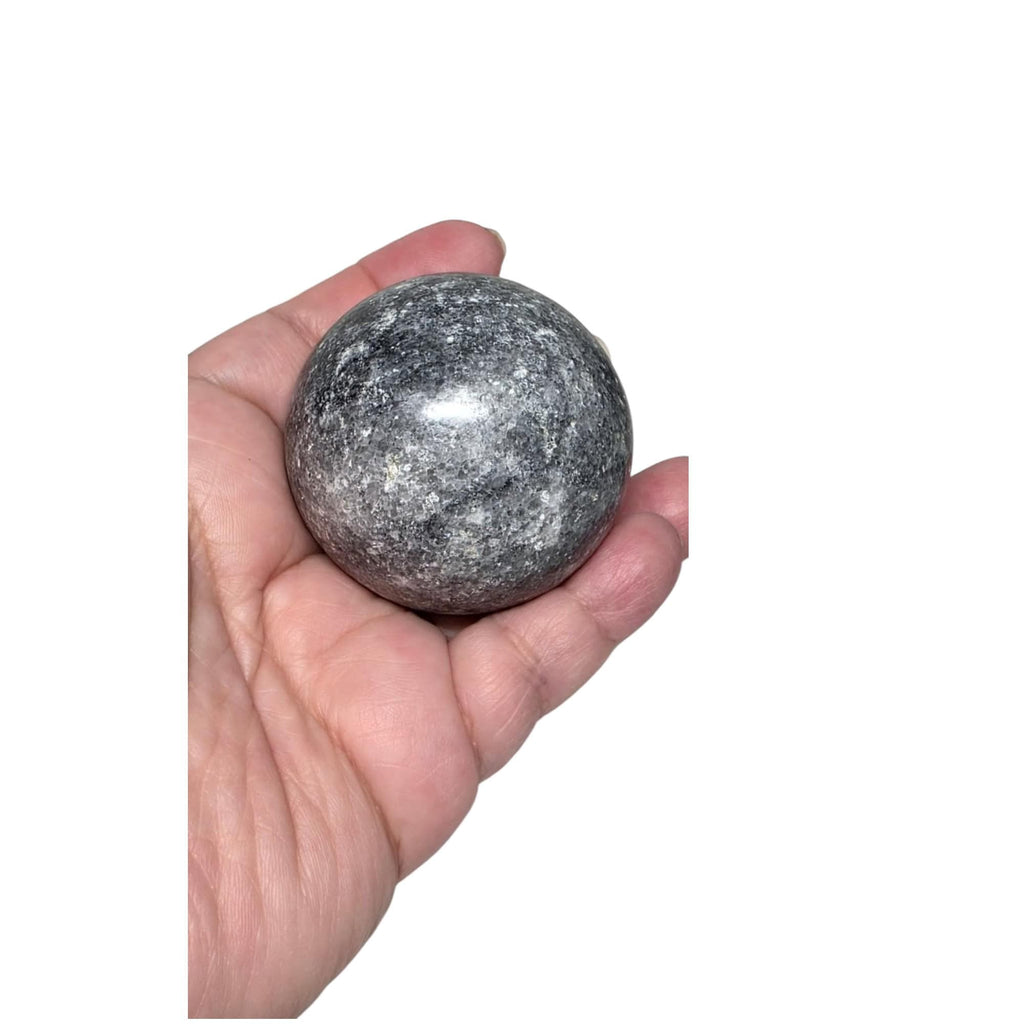 Dark gray jasper crystal ball sphere in hand, speckled stone surface and sheen