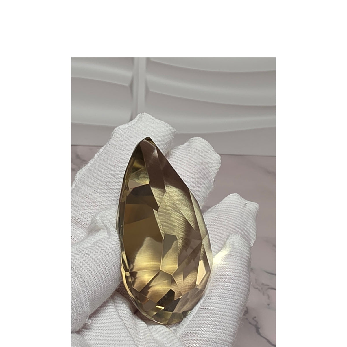 Close view of faceted smoky quartz teardrop held in hand