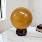 Amber quartz crystal ball with glossy surface on dark pedestal stand