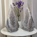 Pair of quartz geode towers with crystal-filled faces and dark gray stone bases