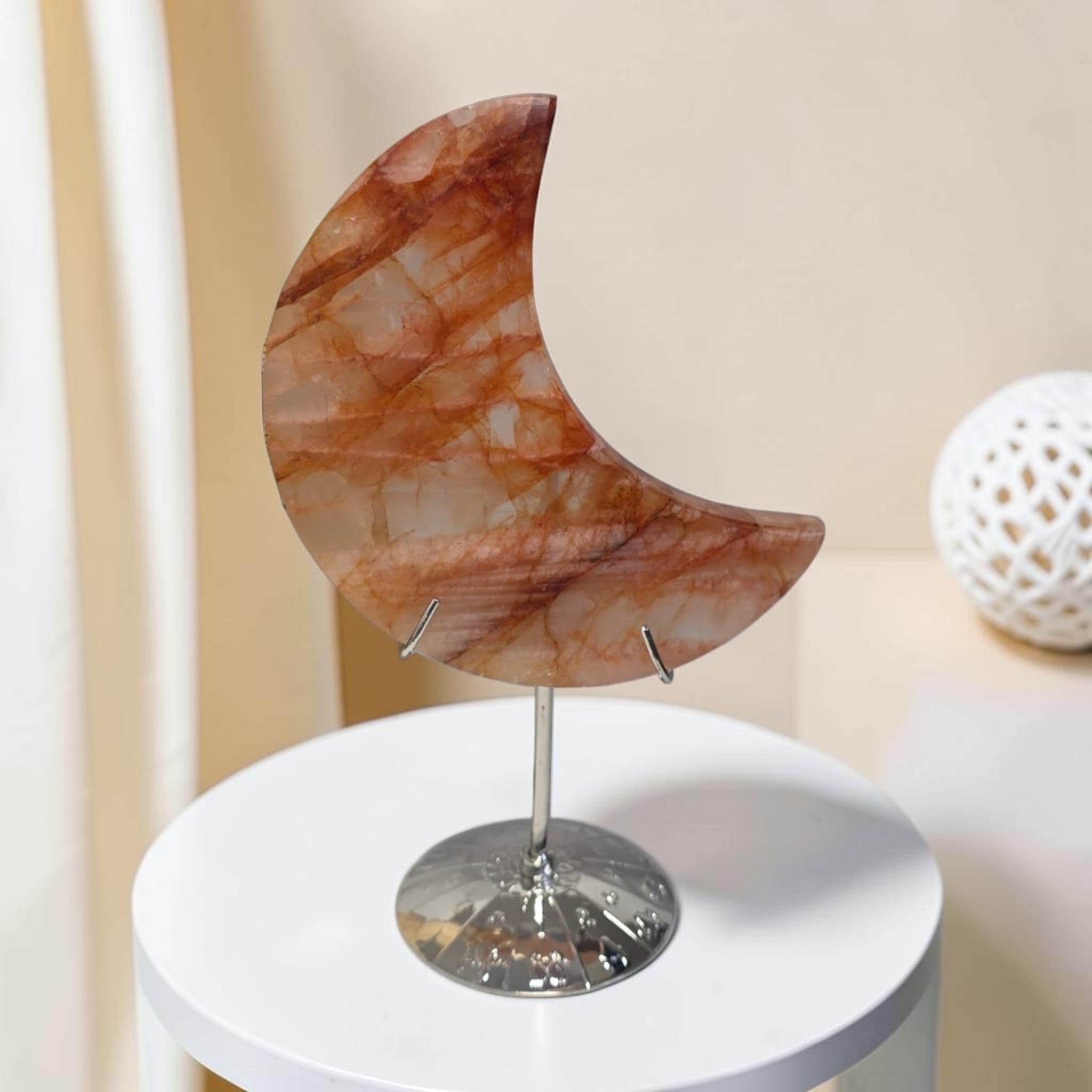 Crescent moon quartz crystal on metal stand, reddish-brown and cream veined surface