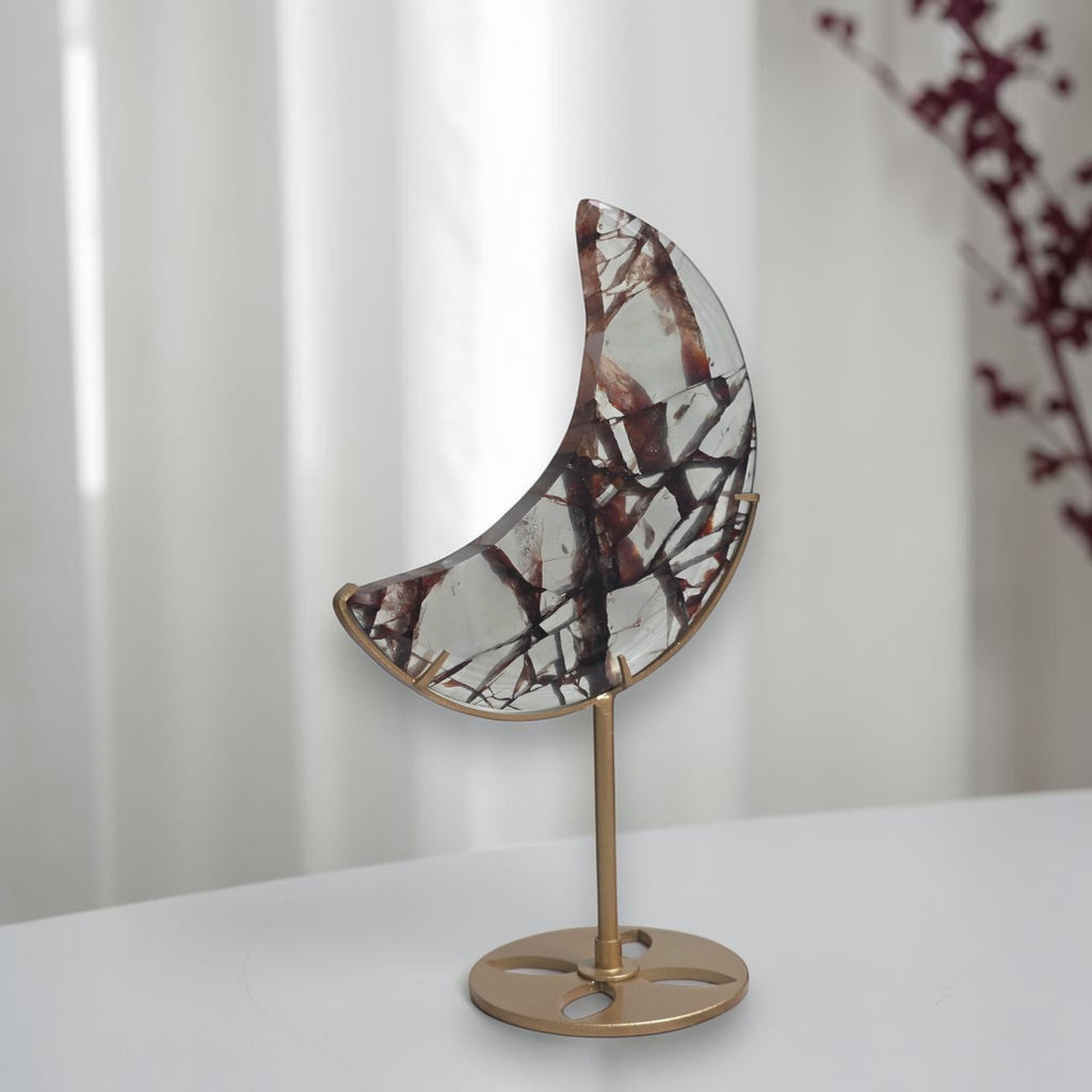 Fire quartz crescent moon displayed on a gold tone stand