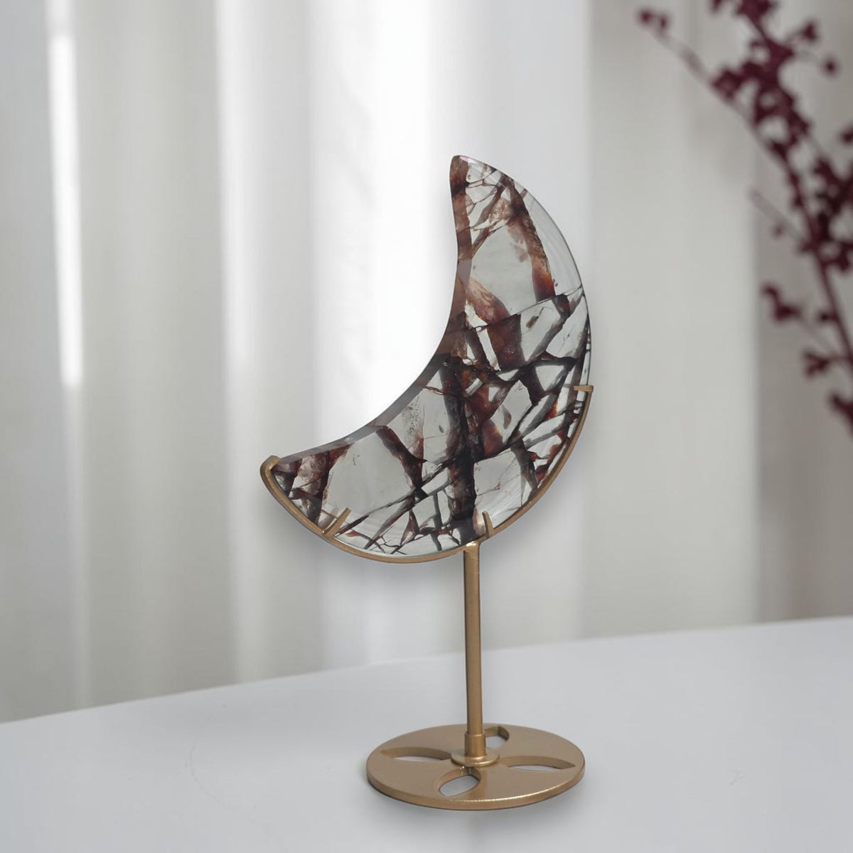 Fire quartz crescent moon displayed on a gold tone stand