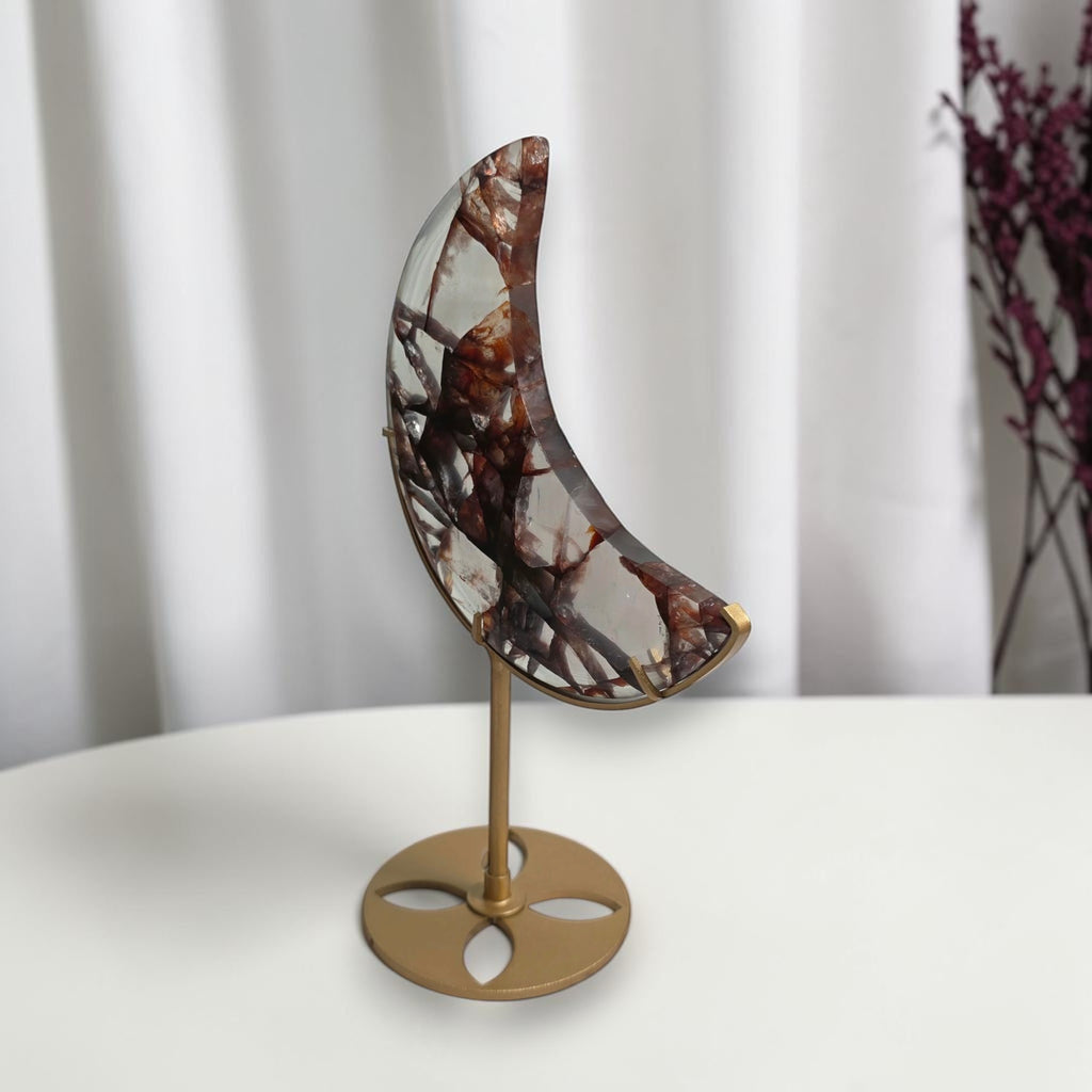 Angled view of the fire quartz crescent moon on its gold tone stand