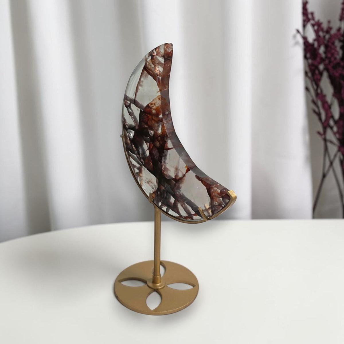 Angled view of the fire quartz crescent moon on its gold tone stand