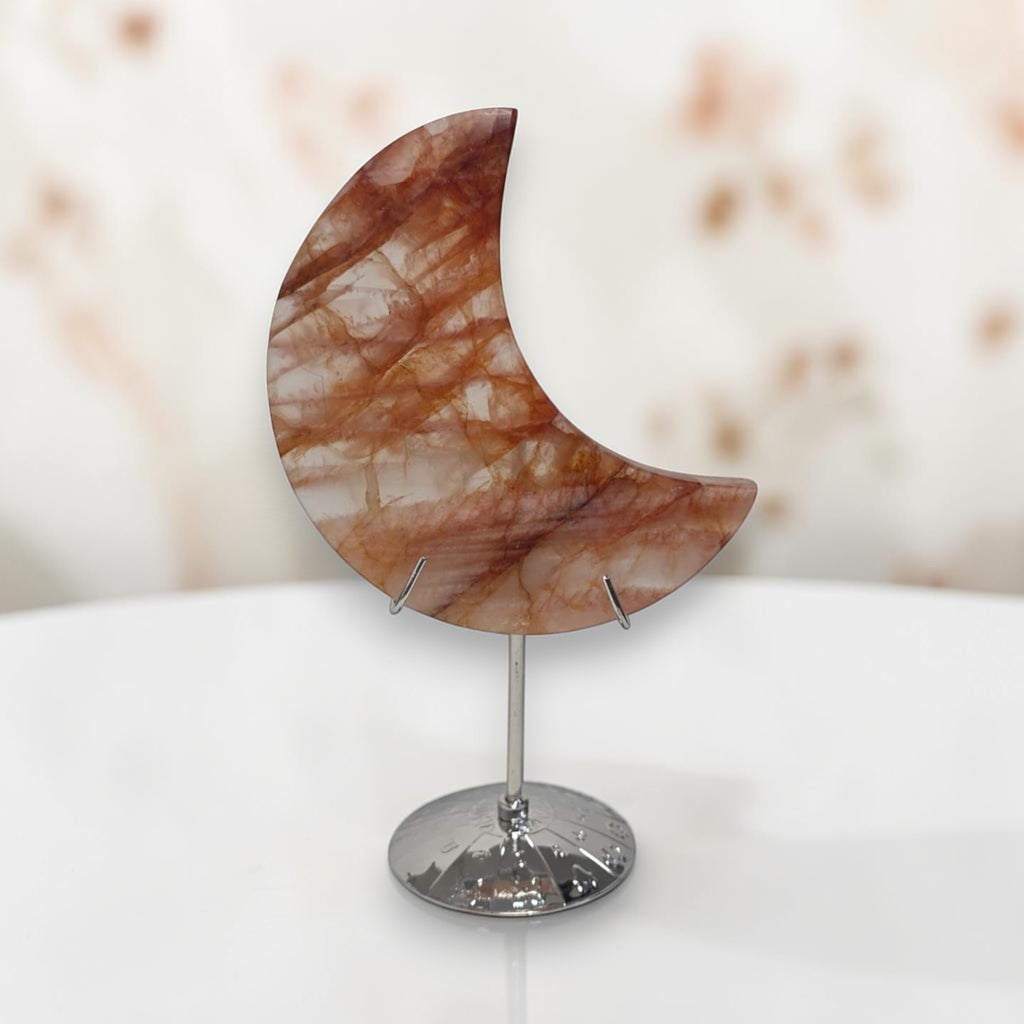 Crescent moon quartz crystal on round base stand, warm orange marbling with metal stem