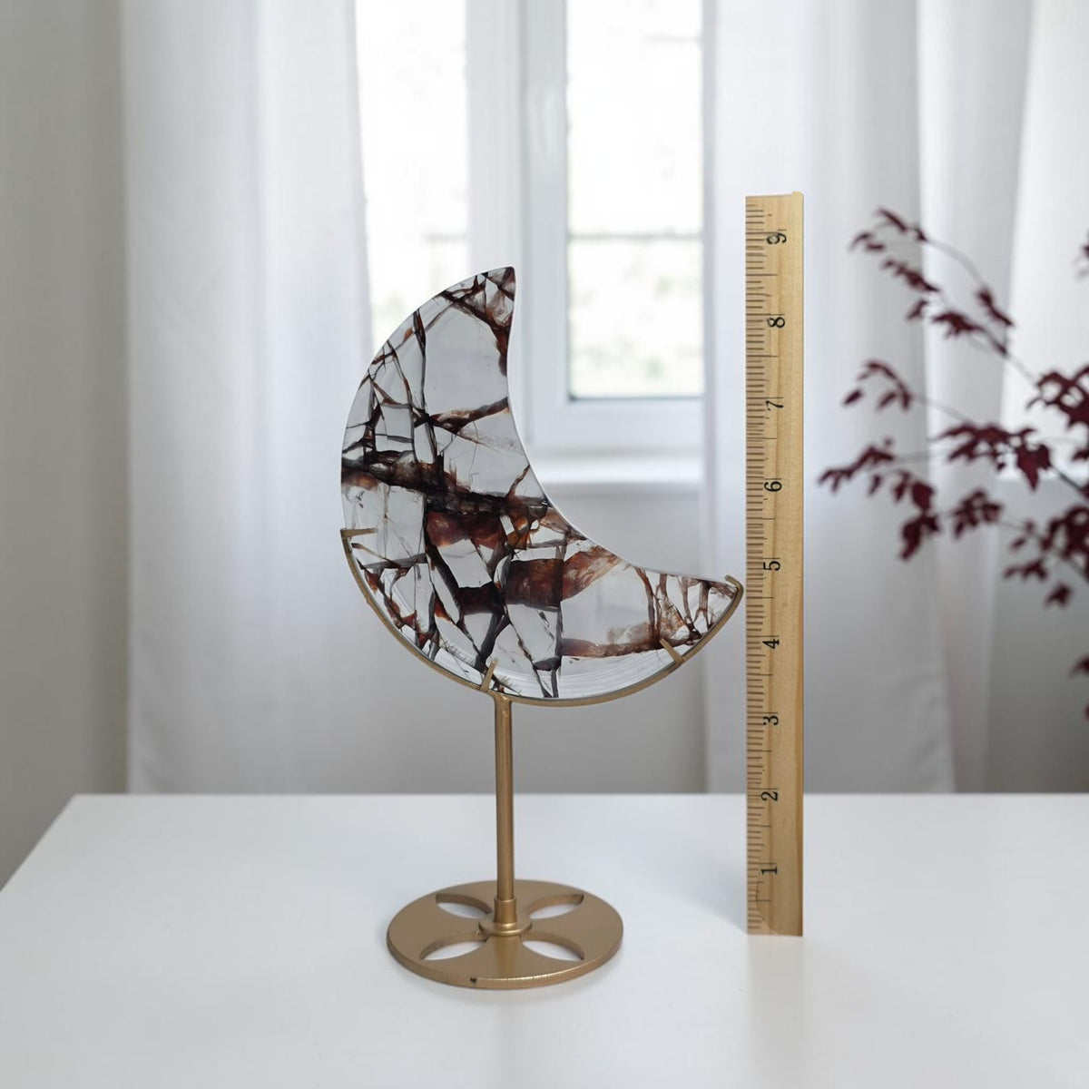 Fire quartz moon on its stand beside a ruler for scale