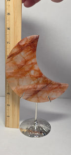 Crescent moon quartz crystal on round metal stand, amber and white marbled pattern