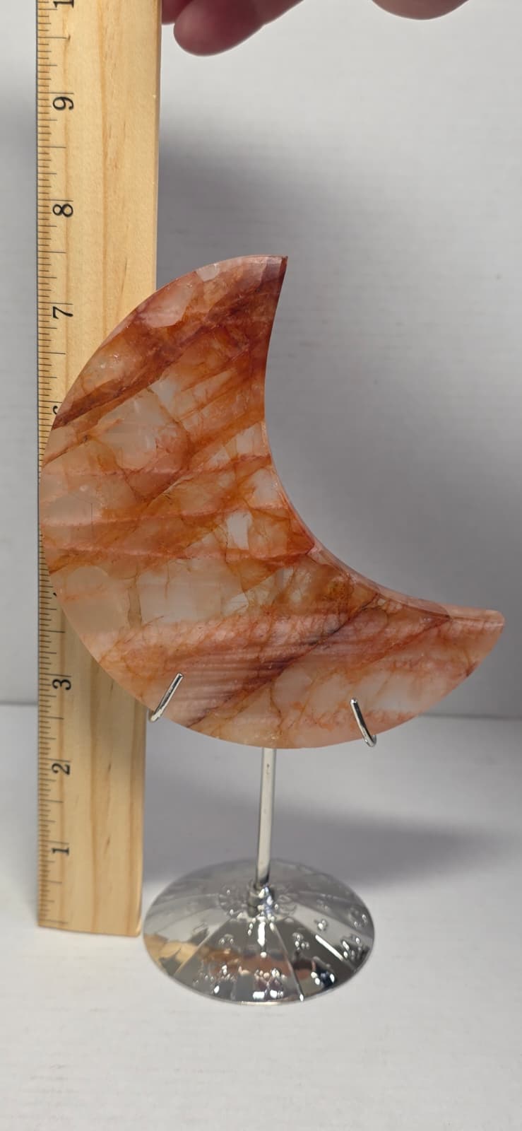 Crescent moon quartz crystal on round metal stand, amber and white marbled pattern