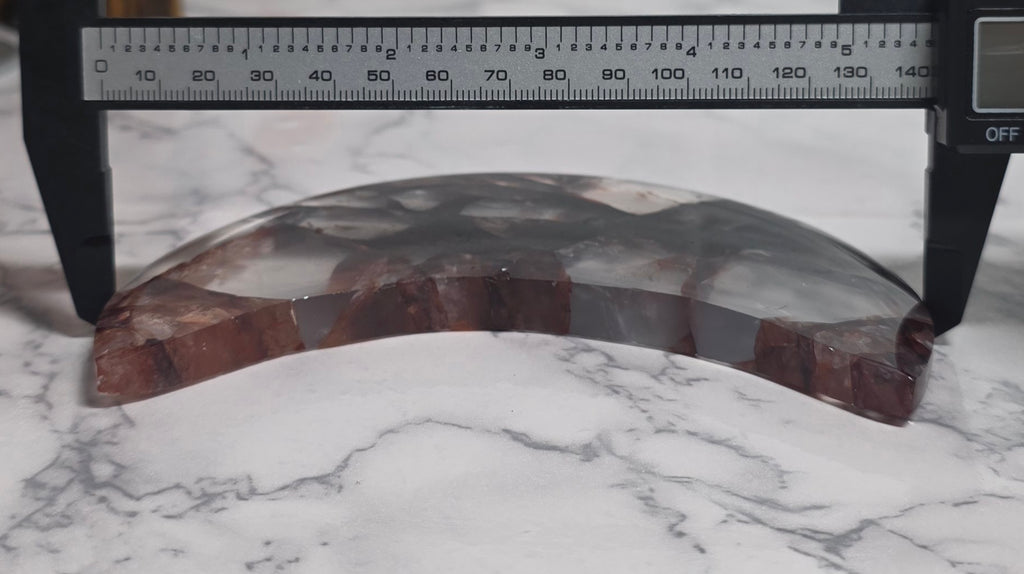 Fire quartz crescent moon shown beside a caliper for scale