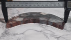 Fire quartz crescent moon shown beside a caliper for scale