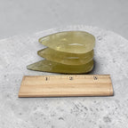 Three yellow crystal slabs with smooth, translucent surfaces beside a 1–3 in ruler