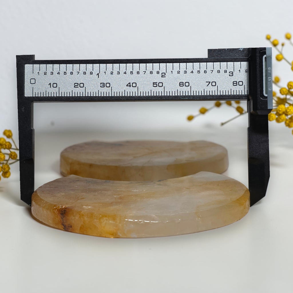 Crescent quartz moon carvings beside a caliper