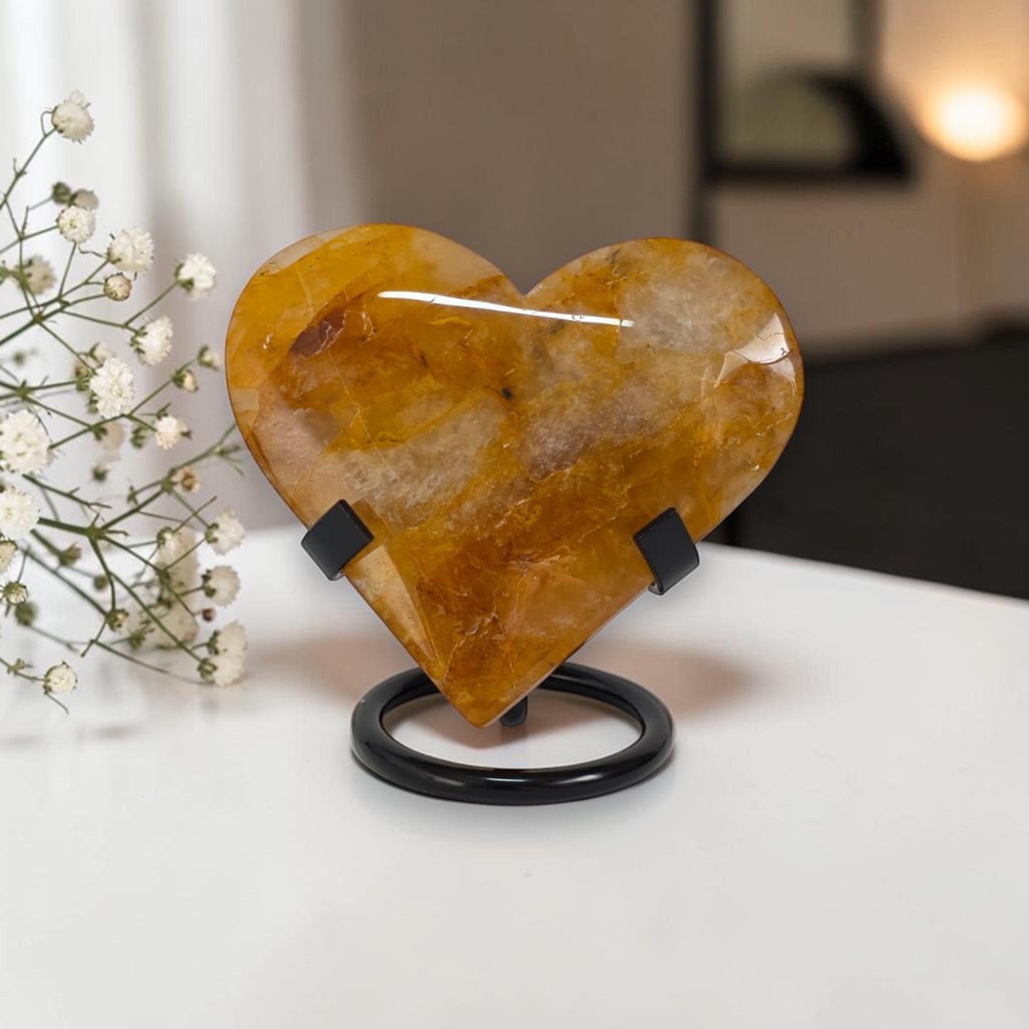 Heart-shaped stone on a stand with white flowers in the background