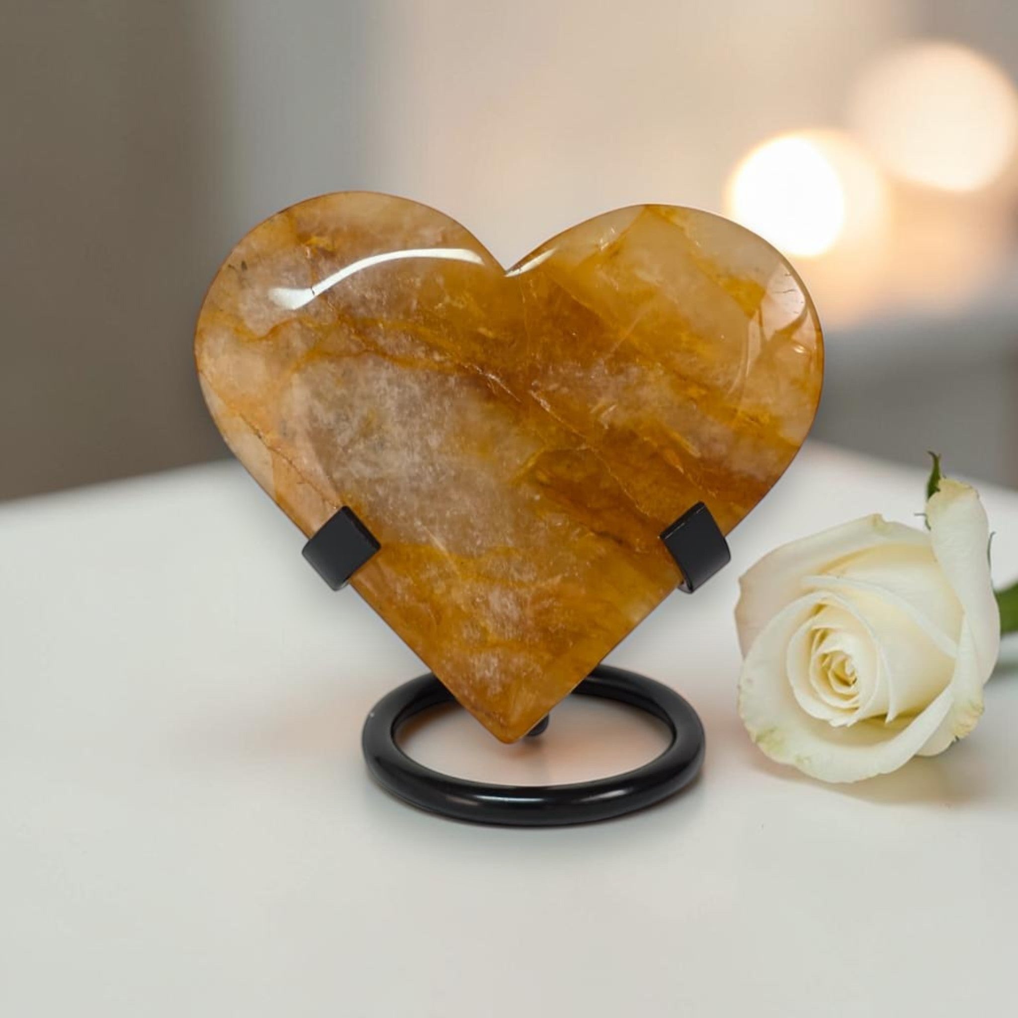 Heart-shaped stone on a stand with a white rose on a light background