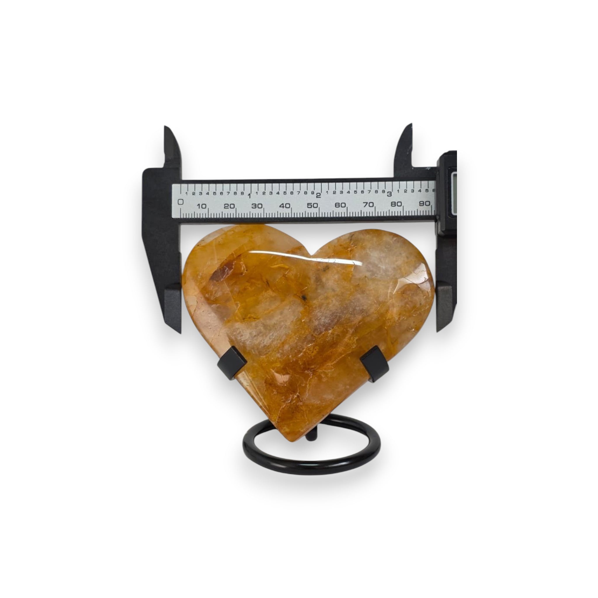 Heart-shaped amber stone with a caliper on a white background