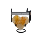 Heart-shaped stone on a stand with a ruler for scale on a white background