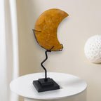 Decorative moon-shaped object on a stand with a white spherical object in the background