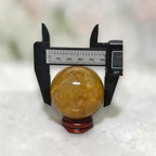 Golden Healer Quartz sphere caliper measurement showing ~50mm diameter