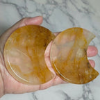Two polished Golden Healer Quartz crescent moon carvings in a hand